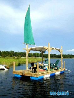 there is a small boat with a green sail on it in the water next to a dock