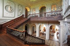 an ornately decorated staircase in the middle of a large room with white walls and wood floors