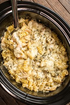 a crock pot filled with macaroni and cheese on top of a wooden table