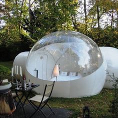 an inflatable bubble tent is set up on the lawn with tables and chairs