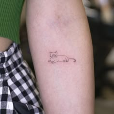 a small cat tattoo on the left inner arm and leg, with an outline of a cat behind it