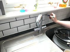 a person is cleaning the kitchen sink with a sponge and a green toothbrush in it