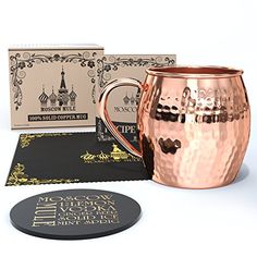 a copper mug next to two coasters and a card board with the word moscow on it