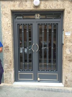 a person standing in front of a building with two doors that have bars on them