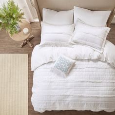 an overhead view of a bed with white comforter and pillows on the floor next to a potted plant