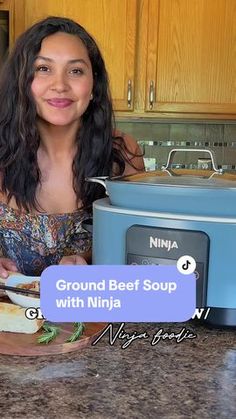 a woman sitting at a kitchen counter in front of an open crock pot with the words ground beef soup with ninja written on it