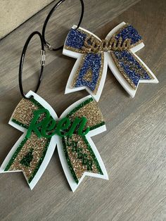 two bows with glitter on them sitting on a wooden table next to a pair of glasses