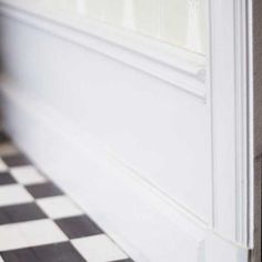 a black and white checkered floor next to a wall with a window in it