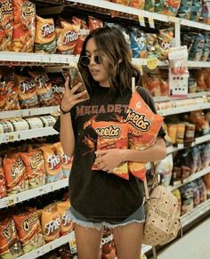 a woman standing in front of a store shelf holding a bag and looking at her cell phone