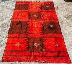 an orange and brown rug sitting on top of a sandy beach