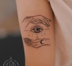 a woman's arm with two hands holding an eye tattoo on the left side of her arm