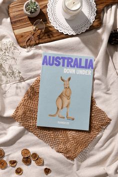 there is a book about australia on top of a bed with other things around it