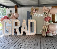 balloons and lights are arranged in the shape of letters that spell out congratulations on a porch