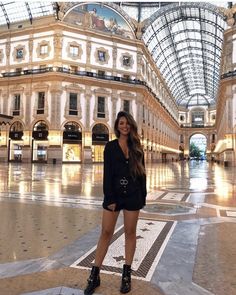 a woman is standing in the middle of a large building with glass ceiling and high ceilings