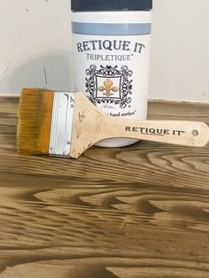 a paintbrush next to a can of retoue it on a wooden table