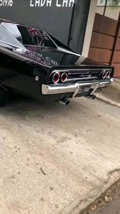 an old black car parked in front of a garage