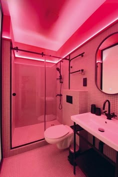 a bathroom with pink lighting on the ceiling and toilet in the shower stall, along with a mirror over the sink