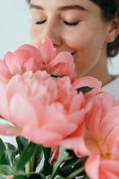 a woman smelling pink flowers with her eyes closed