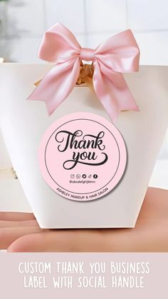 a pink bow on top of a white bag with the words, thank you in it