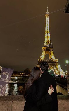 a man and woman standing next to each other in front of the eiffel tower