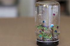 a glass vase with plants inside sitting on a table