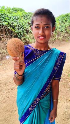 a woman in a blue sari holding a coconut