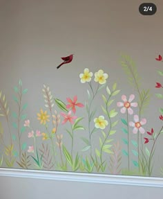 a wall with flowers painted on it and a red bird flying over the flower field