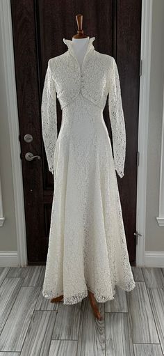 a white dress on a mannequin in front of a door with wooden floors