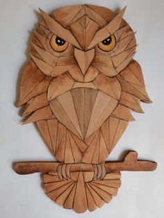 an owl made out of wood sitting on top of a wall