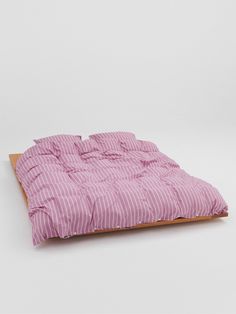 a pink and white striped comforter sitting on top of a wooden frame