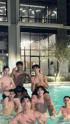 a group of young men standing next to each other in a swimming pool at night