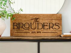 a wooden sign sitting on top of a table next to a potted plant and vase