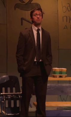 a man in a suit and tie standing next to a table