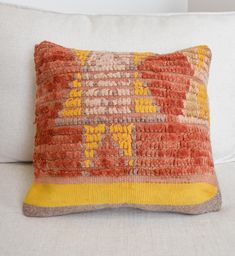 an orange and yellow pillow sitting on top of a white couch