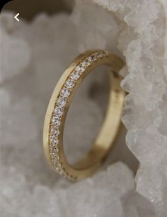 a gold wedding band with white diamonds on top of it, sitting on some crystals