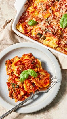 a white plate topped with lasagna next to a casserole dish