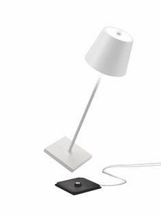 a white lamp sitting on top of a table next to a charger