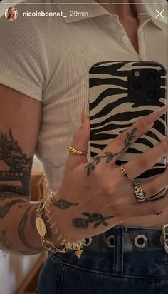 a person holding a cell phone with tattoos on their arms