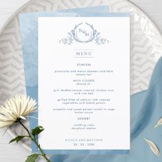 a blue and white plate with a menu card on it next to a flower arrangement