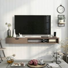 a flat screen tv sitting on top of a wooden shelf in a living room next to a table