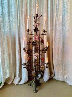 a decorative candle holder with candles in front of a curtained window and curtains behind it