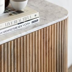 two books are stacked on top of each other near a cup and saucer sitting on a marble table