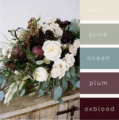 a vase filled with flowers and greenery on top of a wooden table next to a wall