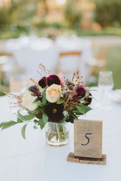 a vase filled with flowers sitting on top of a table next to a wooden block