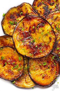 grilled eggplant on a white plate topped with green onions and parsley