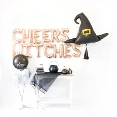 some balloons are sitting on a table near a sign that says cheers witches and a witch's hat