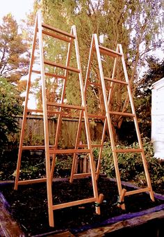 three wooden ladders sitting on top of a garden bed in the middle of a yard