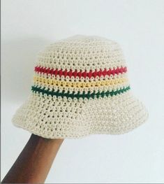 a white crocheted hat with red, yellow, and green stripes on the brim