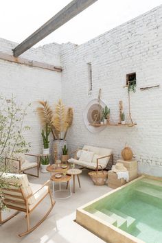 a living room with white brick walls and an indoor swimming pool in the center, surrounded by wooden furniture