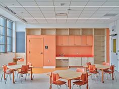 an empty classroom with orange chairs and desks